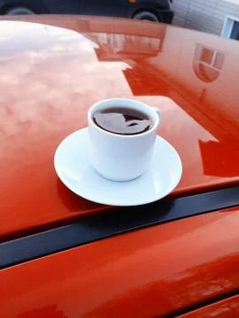 A cup of hot coffee on the background of a red car caravanning concept Stock Photos