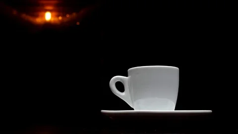 A cup of hot coffee on a black background with a lamp in the background in 4k Stock Footage 91087101