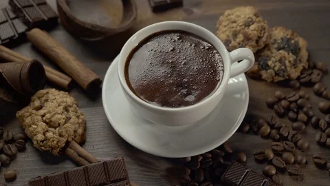 Cup of hot coffee with cinnamon sticks, chocolate slices and cookies on wooden Stock Footage 82191121