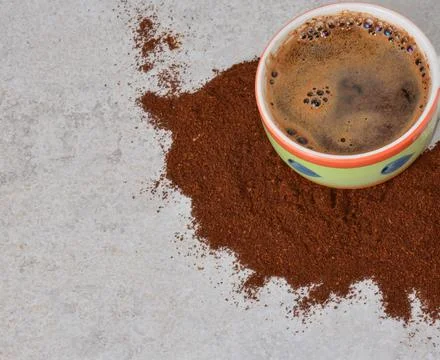 A cup of hot coffee on a gray table around spilled coffee. Stock Photos