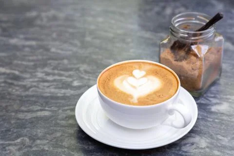 Cup of hot coffee with heart pattern in white cup and brown sugar. Foto stock