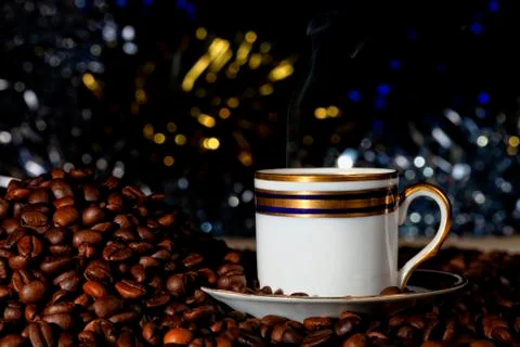 A cup of hot coffee next to a pile of roasted coffee beans Foto stock