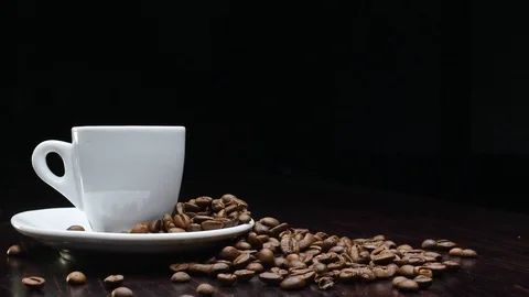A cup of hot coffee with roasted beans around on a black background in 4k Stock Footage 91087390