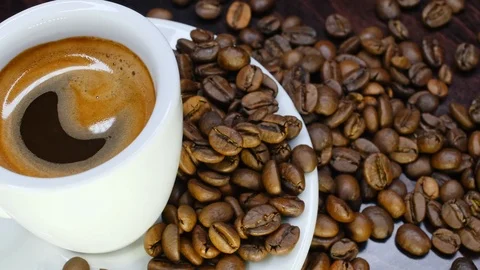 A cup of hot coffee with roasted beans around on a black background in 4k Stock Footage 91087479