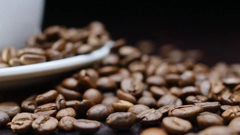 A cup of hot coffee with roasted beans around on a black background in 4k Stock Footage 91087604