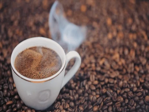 Cup with hot coffee on roasted coffee beans. Slow motion 库存影片 73668652