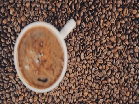 Cup with hot coffee on roasted coffee beans. Slow motion Stock Footage 73669073