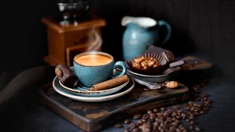 A Cup of hot coffee on a rustic Board with coffee beans and cinnamon sticks Stock Photos