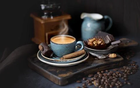 A Cup of hot coffee on a rustic Board with coffee beans and cinnamon sticks Stock Photos
