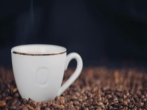 Cup with hot drink on roasted coffee beans. Slow motion 스톡 동영상 73671423
