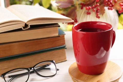Cup with hot drink, stack of books and glasses on white wooden table. Autum.. 스톡 사진