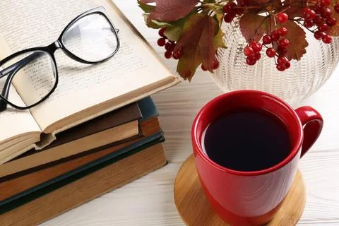 Cup with hot drink, stack of books and glasses on white wooden table, above.. 写真素材