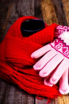 Cup of hot drink wrapped by red scarf and gloves on wooden board Stock Photos