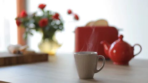 A Cup Of Hot Tea On A Background Of Red Roses Bouquet, Red Kettle And Toaster Stock Footage 100381297