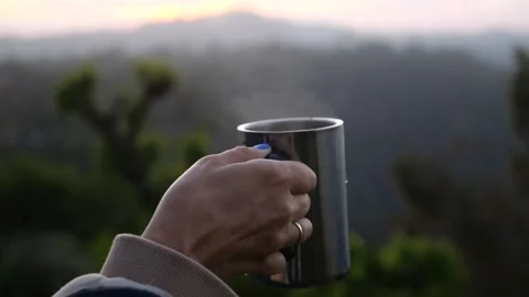 Cup of hot tea close-up against backdrop of a gorgeous mountain landscape at Stock Footage 253777585