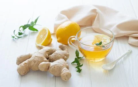 Cup of hot tea with ginger root, lemon and mint on white wooden table Foto stock