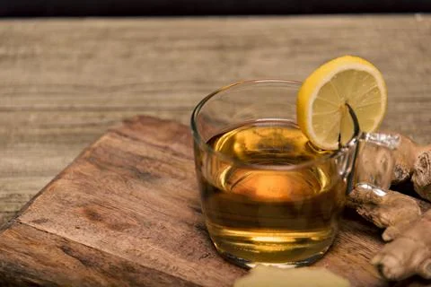 Cup of hot tea with ginger root, lemon and curcuma. Adding natural raw honey to Stock Photos