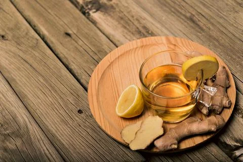Cup of hot tea with ginger root, lemon and curcuma. Adding natural raw honey to Stock Photos