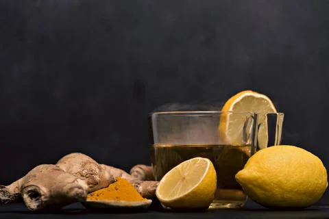 Cup of hot tea with ginger root, lemon and curcuma. Adding natural raw honey to Stock Photos
