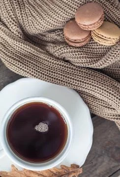 A cup of hot tea, macaroons, a knitted sweater on a wooden table. Autumn. W.. Stock Photos