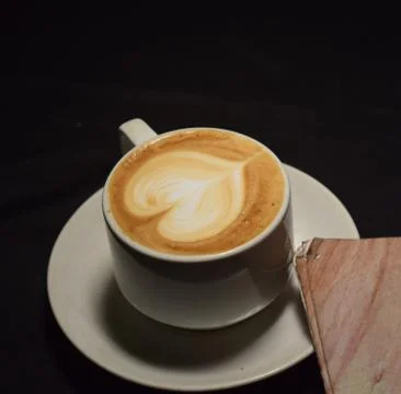 A cup of latte art with heart pattern in a white cup.Indoor cafe Fotos de archivo