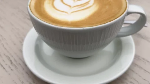 A cup of latte with latte art in the shape of a leaf or feather in the milk foam Stock-Footage 317384276