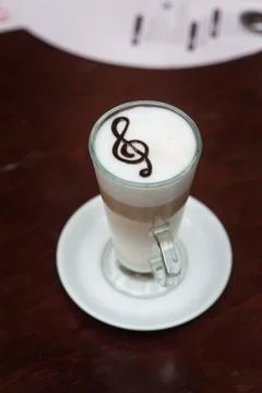 Cup of latte with a treble clef on the table Stock Photos