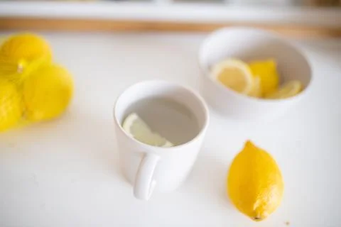Cup of lemon tea on a white table surrounded by lemons Stock-Fotos