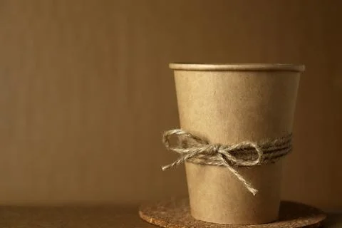 Cup made of kraft paper with a string tied around its body on a cork coaster Stock Photos