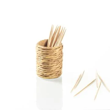 Cup made of straw for toothpicks with reflection in a white mirror background Stock Photos