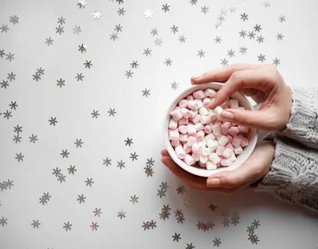Cup with marshmallows on a white background with silver snowflakes Stock Photos