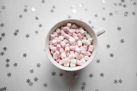 Cup with marshmallows on a white background with silver snowflakes Stock Photos