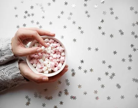 Cup with marshmallows on a white background with silver snowflakes Stock Photos