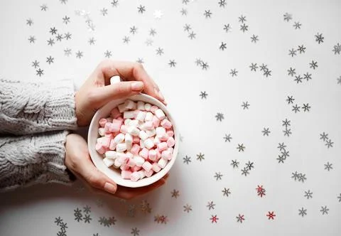 Cup with marshmallows on a white background with silver snowflakes Stock Photos