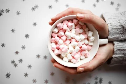 Cup with marshmallows on a white background with silver snowflakes Stock Photos