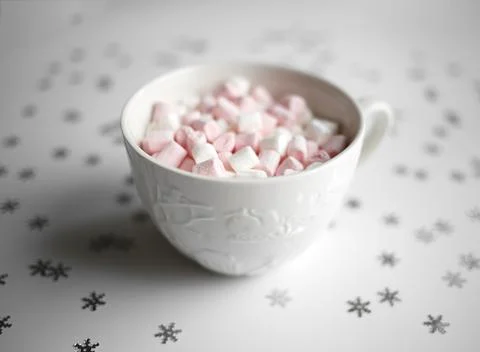 Cup with marshmallows on a white background with silver snowflakes Stock Photos