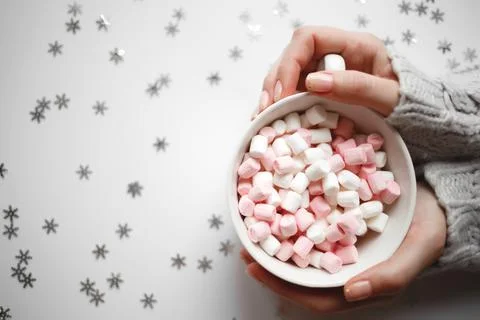 Cup with marshmallows on a white background with silver snowflakes Stock Photos