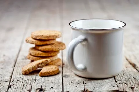 Cup of milk and stack of fresh baked oat cookies on rustic wooden table backg Stock Photos