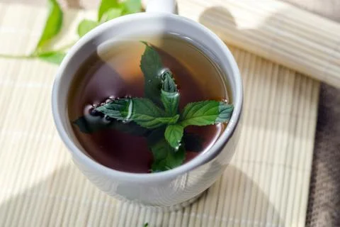 Cup of mint tea and a bunch of mint on the table Stock Photos