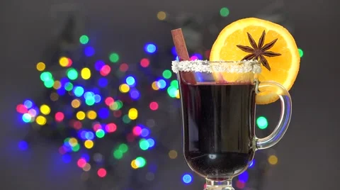 Cup of mulled wine with slice of orange and cinnamon, blur lights in background Video stock 67370598