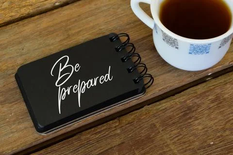 A cup of nescafe and notebook written with BE PREPARED. Stock Photos