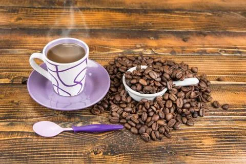 Cup od coffe with roasted bean on the wooden table. Stock Photos