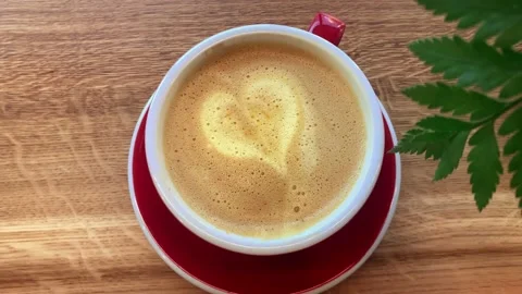 Cup of orange coffee latte with latte art: heart foam on coffee surface Vídeos de archivo 169452287
