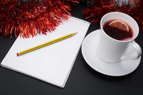 Cup of red tea with lemon slice, notebook with pencil, red and white christma Stock Photos