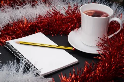 Cup of red tea with lemon slice, notebook with pencil, red and white christma Stock Photos
