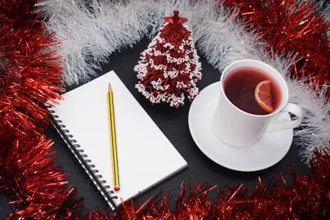 Cup of red tea with lemon slice, notebook with pencil, red and white christma Foto stock