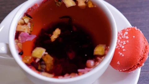 Cup of red tea with red macaroon on wooden table in cafe Stock Footage 106463180