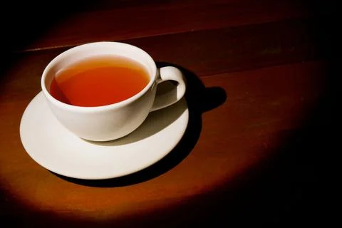 A cup of refreshing black tea, warm soft light, dark wood background. Stock Photos