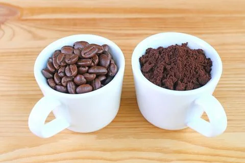 Cup of Roasted Coffee Beans with a Cup of Ground Coffee on Wooden Background 스톡 사진