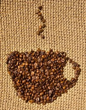 Cup-shaped coffee roasted beans on a knitted pattern in beige raffia. Hand .. Stock Photos